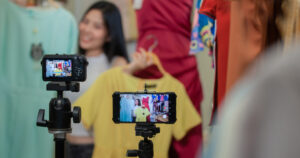 Woman filming herself showing items of clothing on a live shopping stream